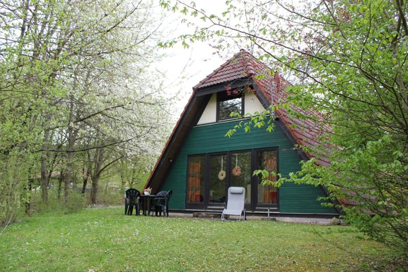 a green house with a table and chairs in front of it at Ferienhaus Kirschblüte in Ronshausen