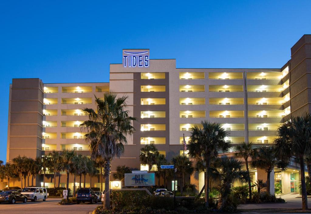 a hotel building with palm trees in front of it at Tides Folly Beach in Folly Beach