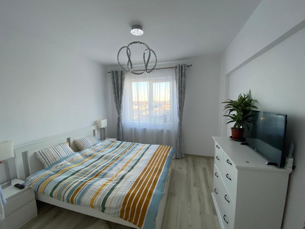Libertatii 88 Luxury Apartment في Bragadiru: غرفة نوم بسرير وتلفزيون وخزانة