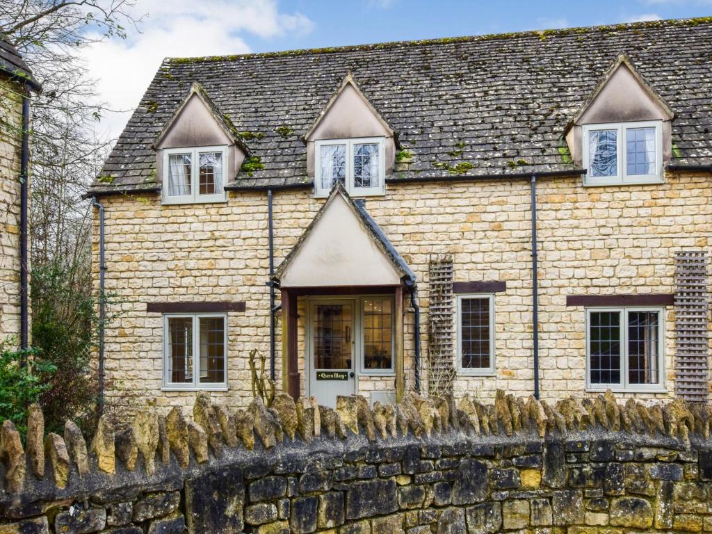 a stone house with a stone fence in front of it at Queen Mary in Winchcombe