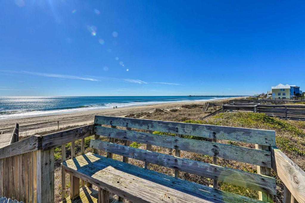 a wooden bench sitting on the side of a beach at Hannahs Place - Quaint and Cozy Apt by the Beach! in Emerald Isle