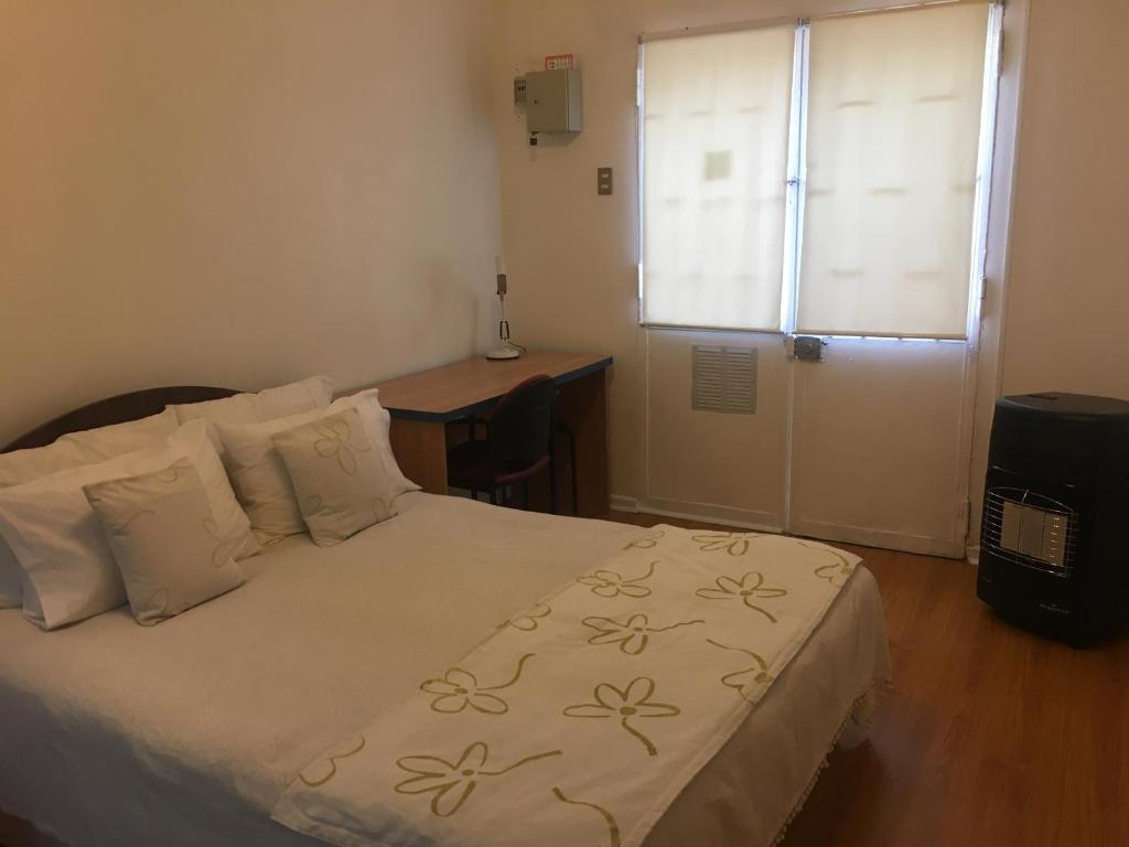 een slaapkamer met een bed, een bureau en een raam bij Avenida Marina 1 in Viña del Mar