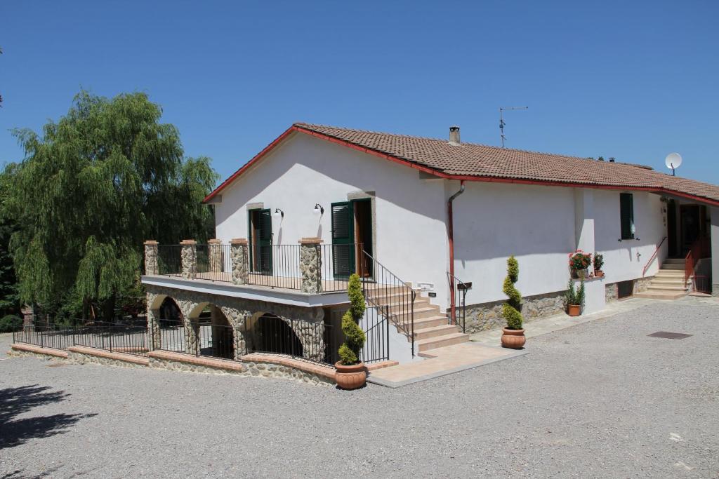 a white house with a porch and a balcony at Agriturismo Le Paicciole in CastellʼAzzara