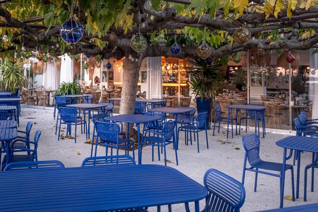 a group of blue tables and chairs under a tree at Hôtel La Reine Jane in Hyères