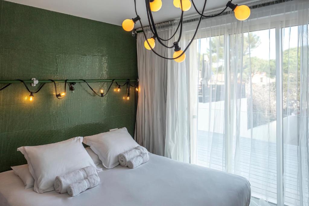 a bedroom with a bed with white pillows and a window at Hôtel La Reine Jane in Hyères