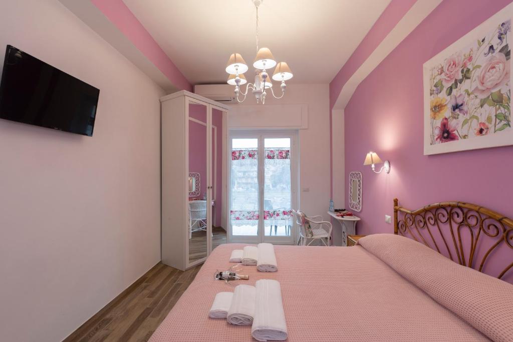 a bedroom with a pink room with a bed and a tv at ViOletta in Lido di Ostia