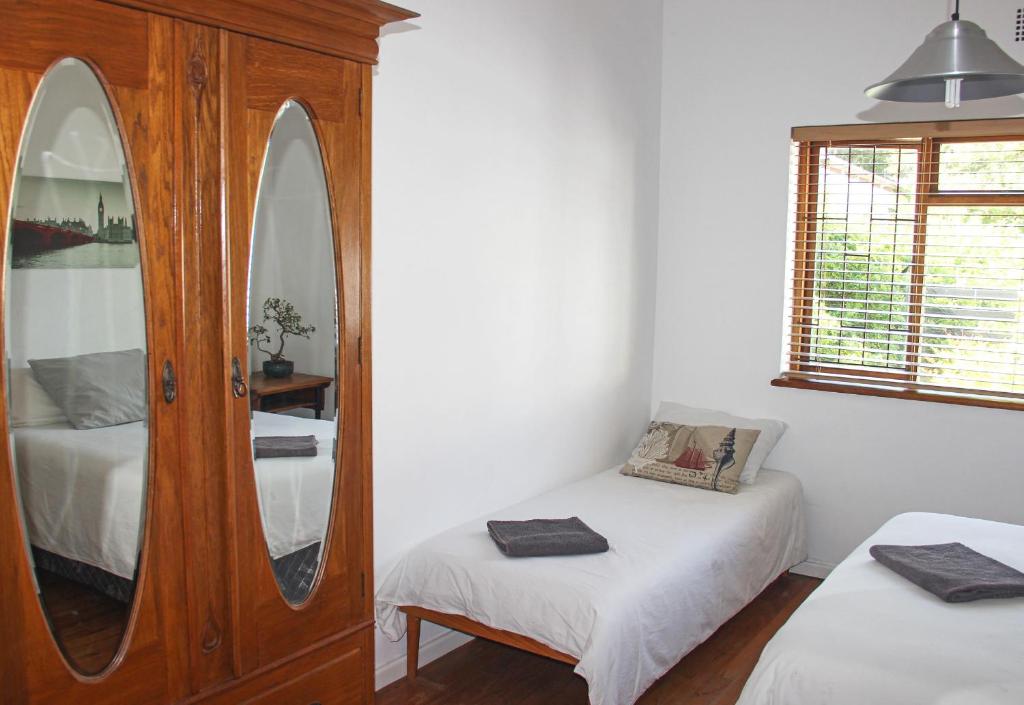 a bedroom with a mirror and two beds in it at Norfolkden Beachhouse in Hermanus
