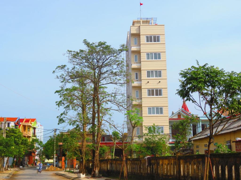 ein hohes weißes Gebäude mitten in einer Stadt in der Unterkunft Nam Long Plus Hotel in Dong Hoi