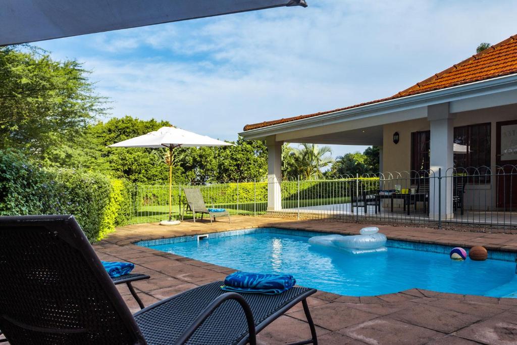 piscina con sedie e ombrellone di Oyster Cottage a Durban