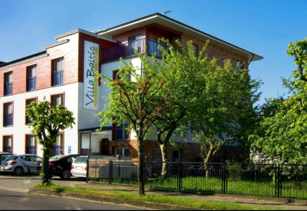 a building with cars parked in front of it at Villa Baltic - Apartament Chałupy nr 6 in Chałupy