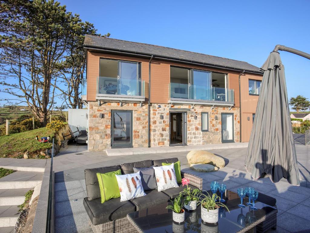 een huis met een patio met een bank en een parasol bij Hafod Y Mor in Criccieth