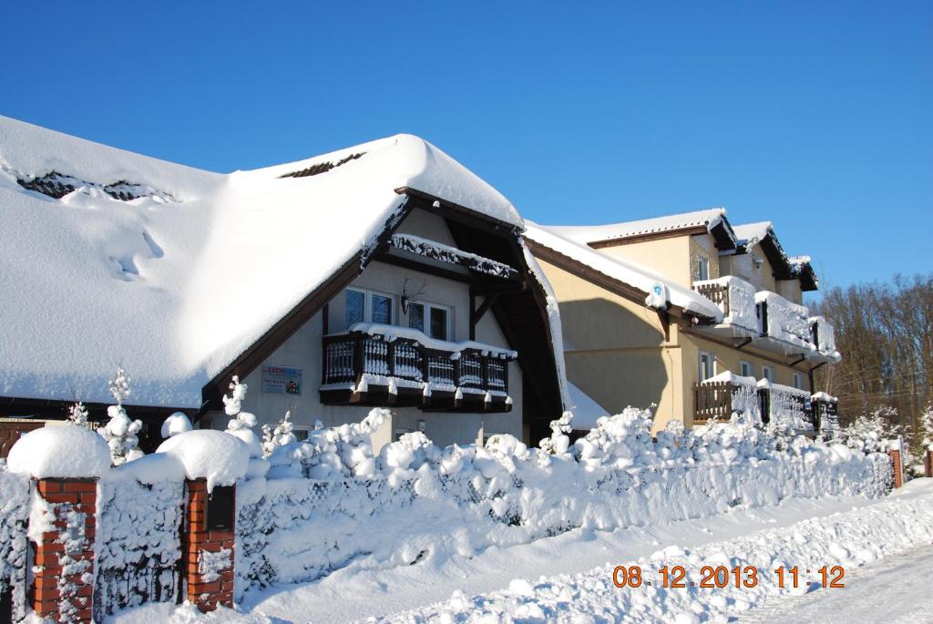 a house covered in snow next to a fence at Zajazd i Restauracja "Myśliwskie Zacisze" in Nikielkowo