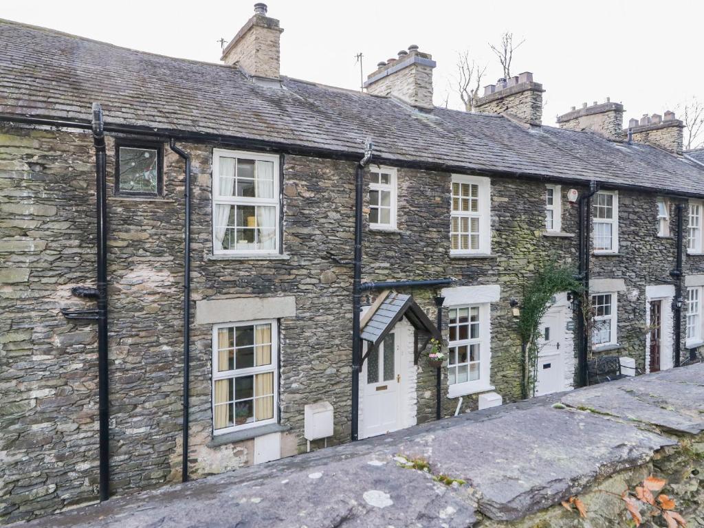an old stone house with white doors and windows at Dalesway Cottage in Windermere