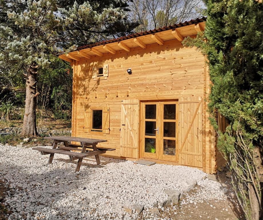 a wooden cabin with a picnic table and a bench at La cabane des Pachous in Tourves