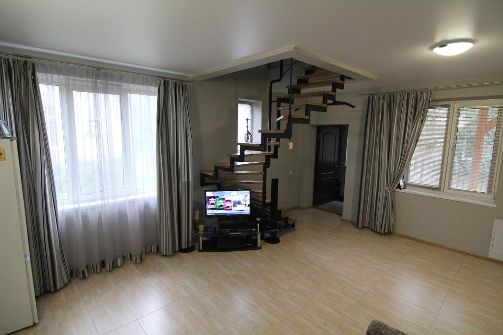 a living room with a spiral staircase and a television at WOW House Lviv in Lviv
