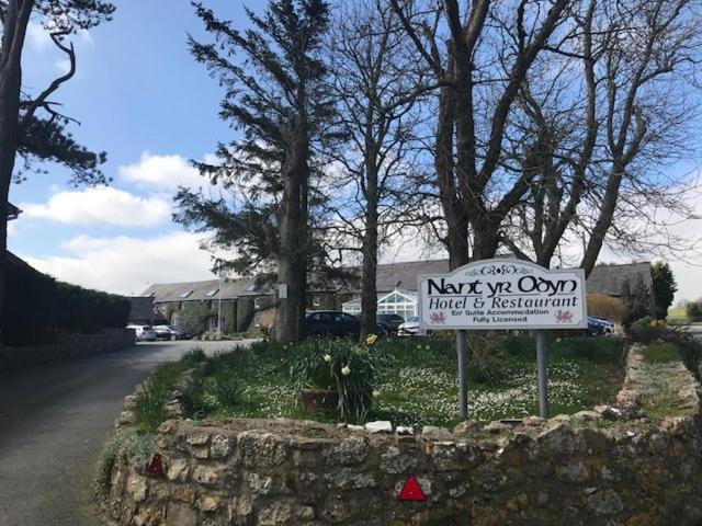 um sinal no lado de uma estrada ao lado de uma casa em Nant Yr Odyn Country Hotel & Restaurant Ltd em Llangefni