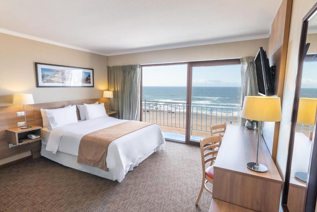 a hotel room with a bed and a balcony with the ocean at Geotel Antofagasta in Antofagasta