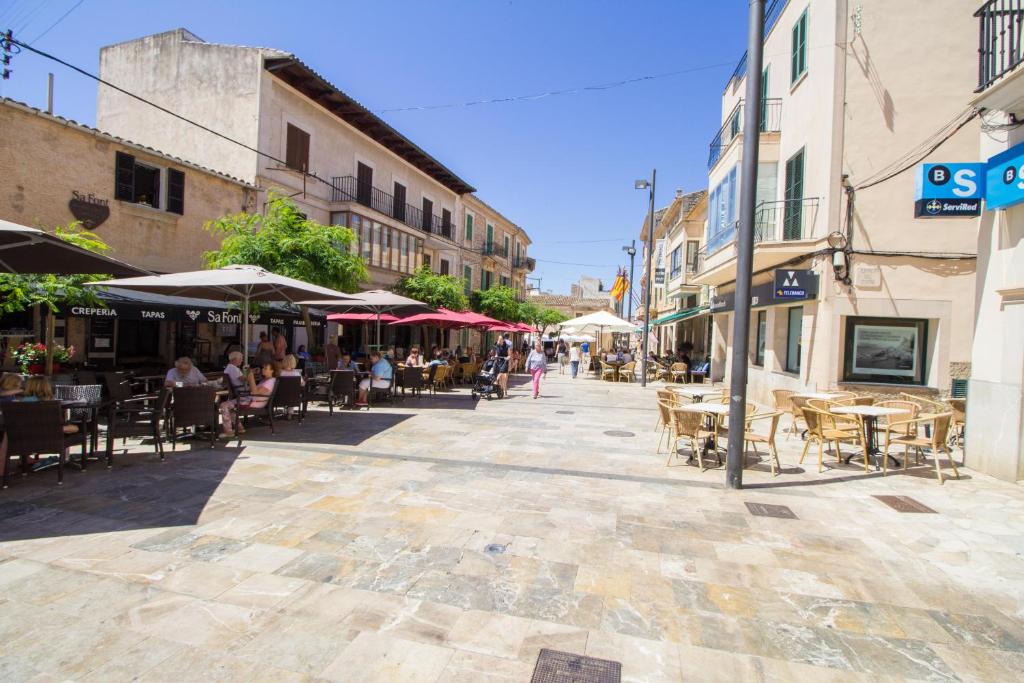 una strada vuota con tavoli, sedie e ombrelloni di Casa típica Mallorquina con mucho encanto a Santanyi