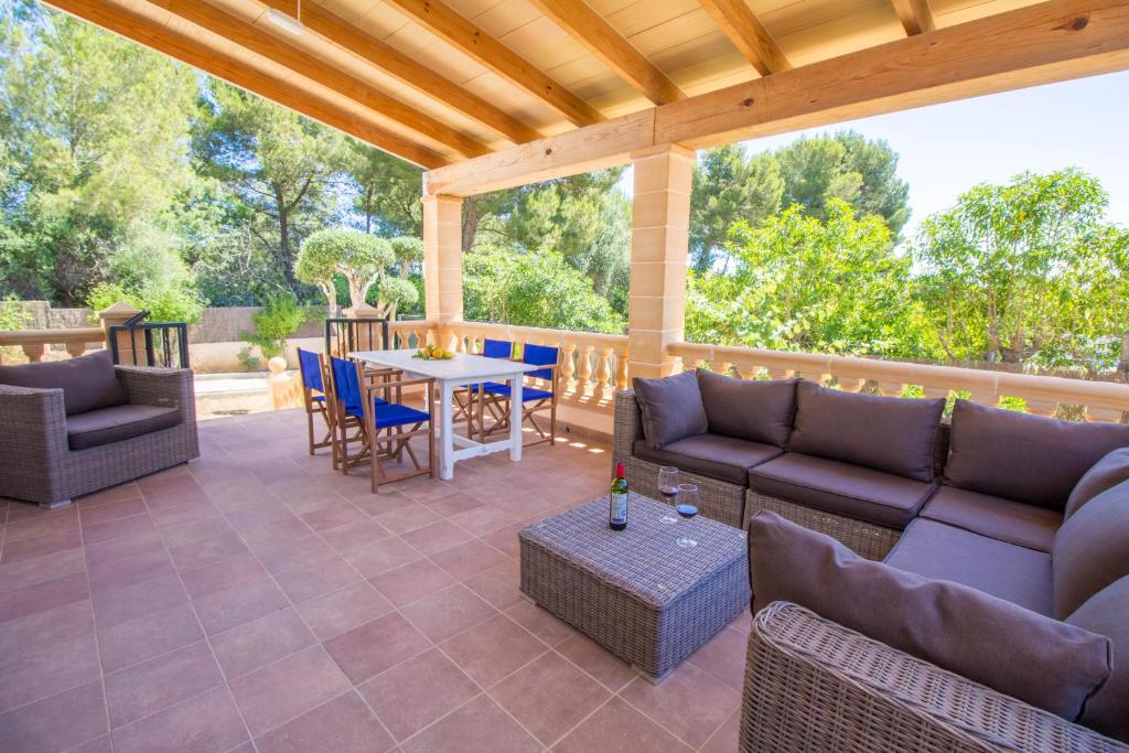 a patio with couches and a table and chairs at Bonito Chalet con WiFi muy cerca del mar in Font de Sa Cala