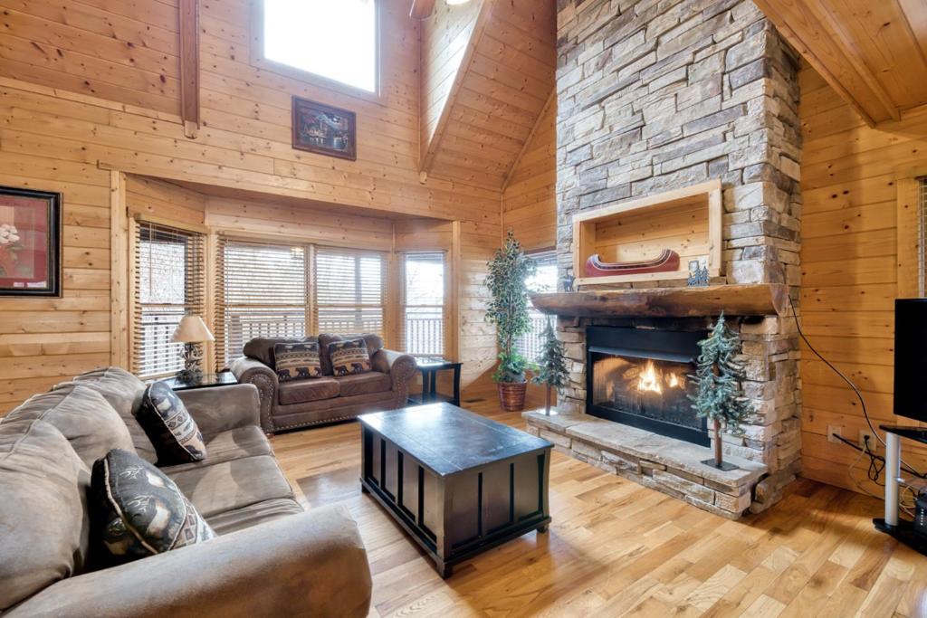 a living room with a fireplace in a log cabin at Country Living by Venture Smoky Mountains in Sevierville