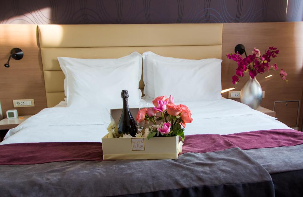 a bed with a bottle of wine and flowers on it at Hotel Srbija Garden-FREE PARKING in Belgrade