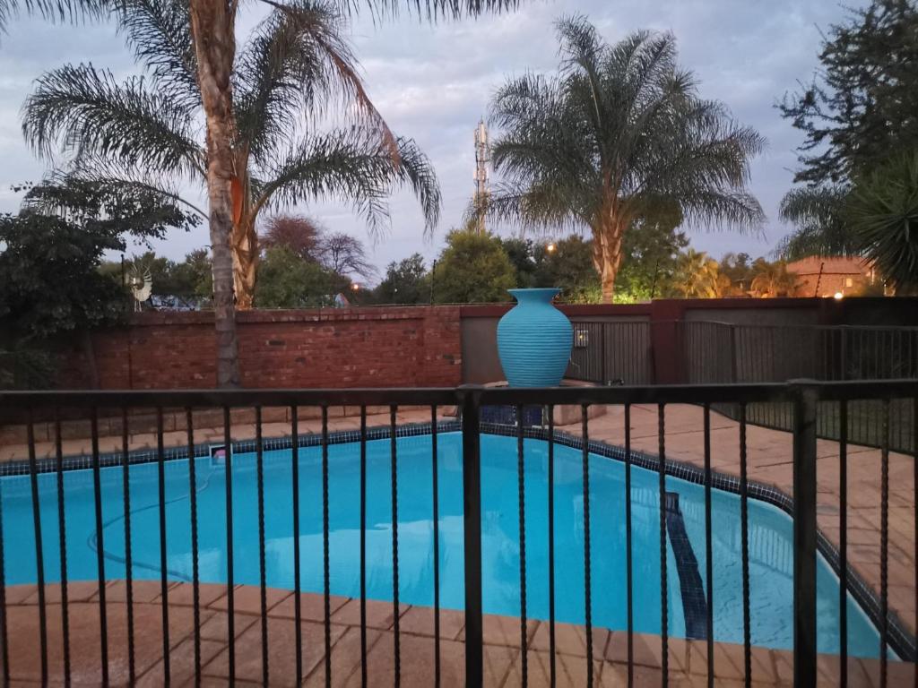 a blue vase sitting on a fence next to a pool at Klyne Jiweel Guesthouse in Pretoria