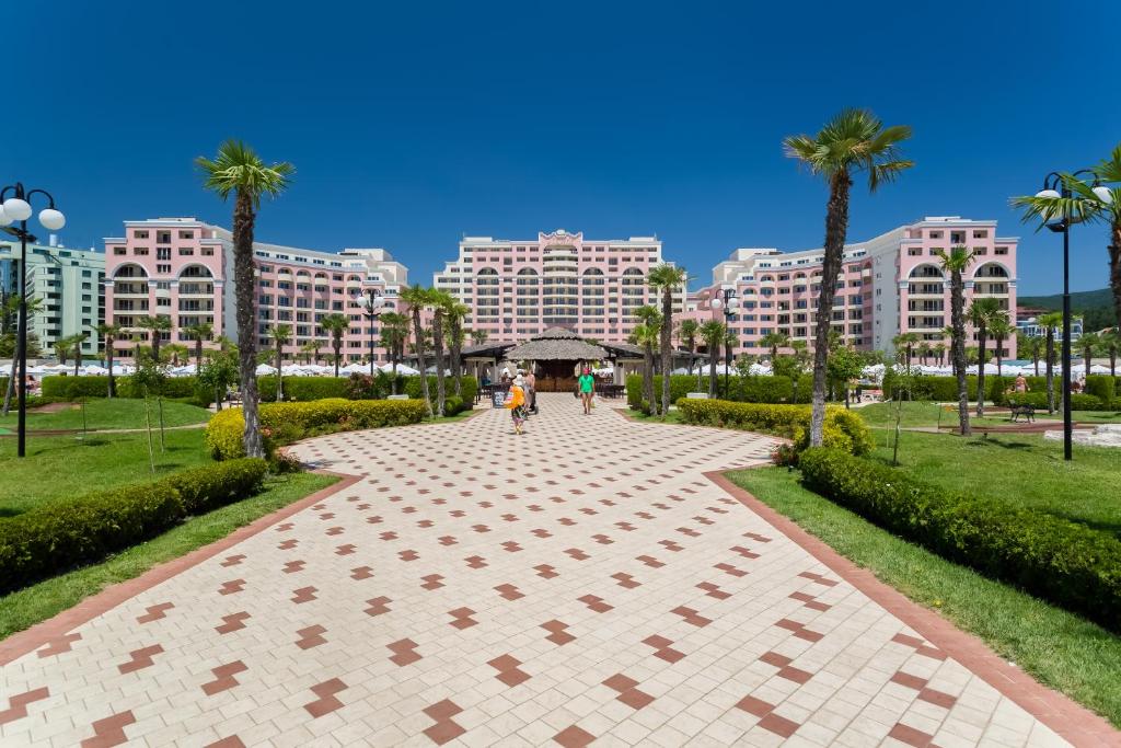 una pasarela en un parque con palmeras y edificios en DIT Majestic Beach Resort - Ultra All Inclusive, en Sunny Beach