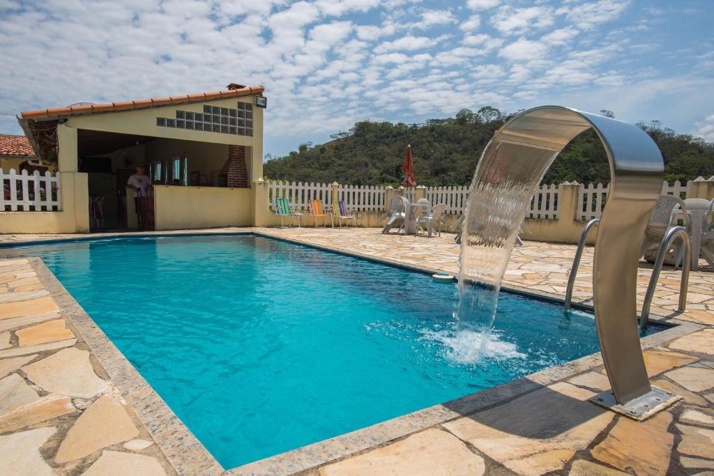 una piscina con una fuente de agua en un patio en Pousada Marinho Society en Paty do Alferes