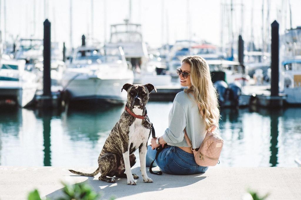 a woman sitting on a dock with her dog at The Perry Hotel & Marina Key West in Key West