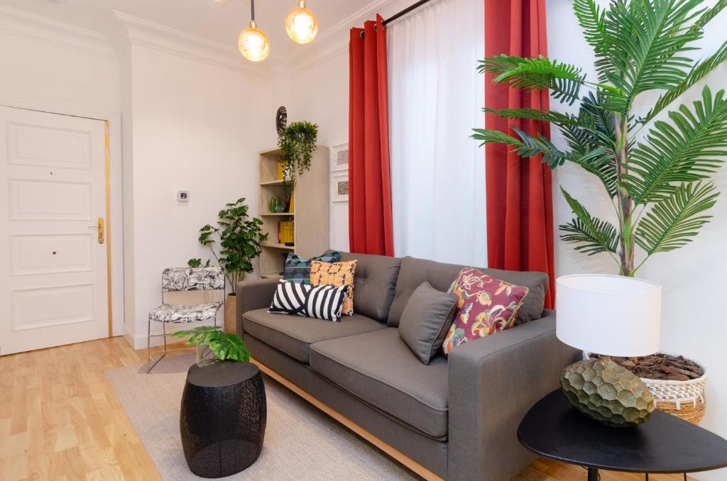 a living room with a gray couch and a palm tree at Palacio Premium Stay in Madrid