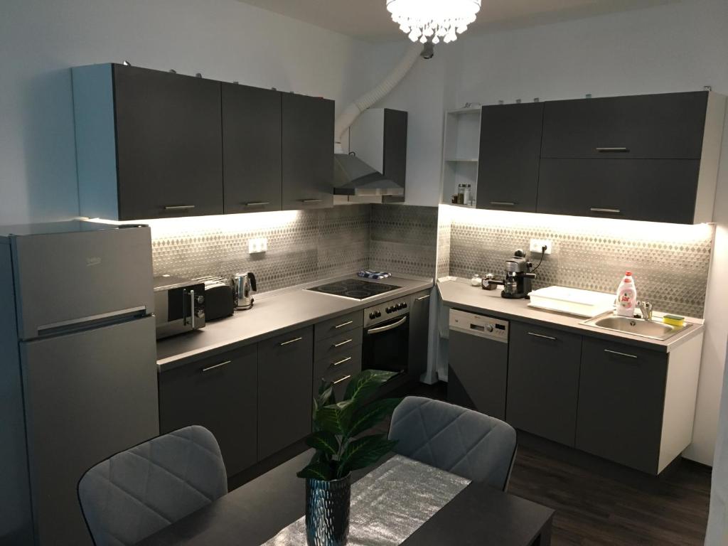a kitchen with black cabinets and a table with chairs at Queen Apartman in Debrecen