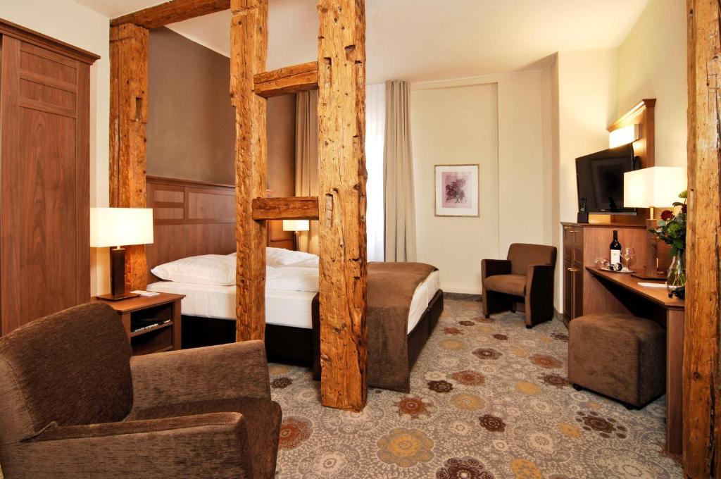 ローテンブルク・オプ・デア・タウバーにあるホテル ブルクガルテンパレの四柱式ベッド1台と椅子が備わるホテルルームです。