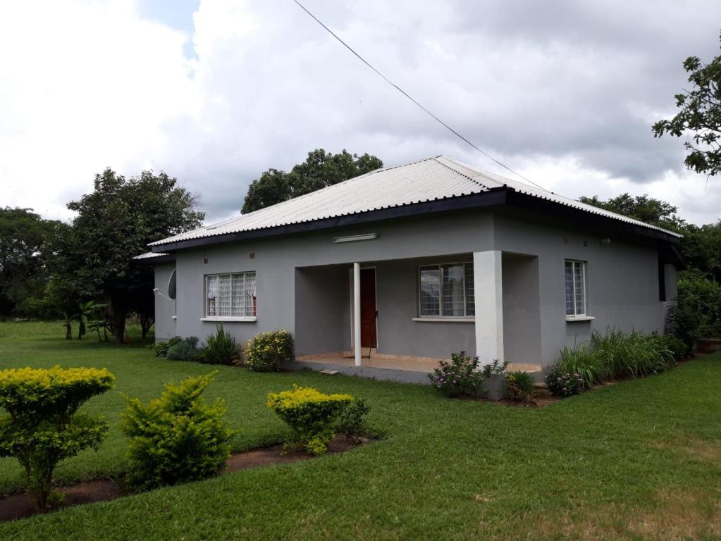 una piccola casa bianca con un cortile verde di Sheilas home away from home a Lusaka