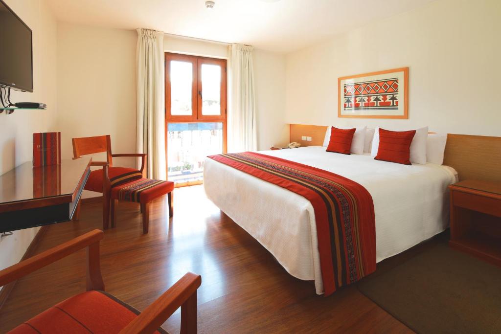 um quarto de hotel com uma cama grande e uma secretária em San Agustin Plaza em Cusco
