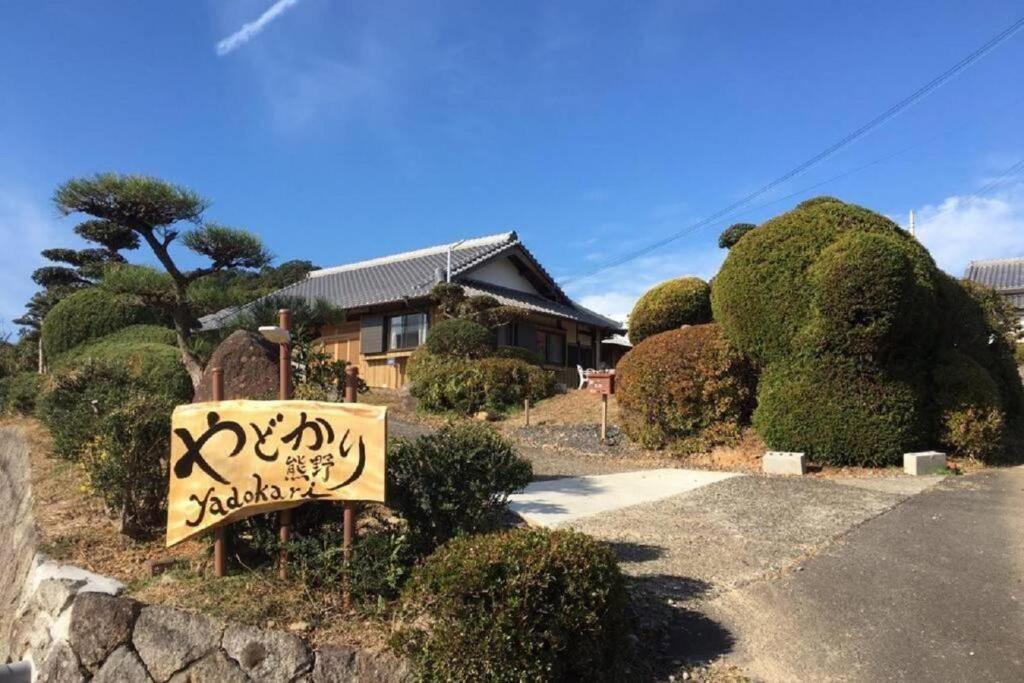 ein Haus mit einem Schild vor einem Hof in der Unterkunft Yadokari Kumano in Kumano