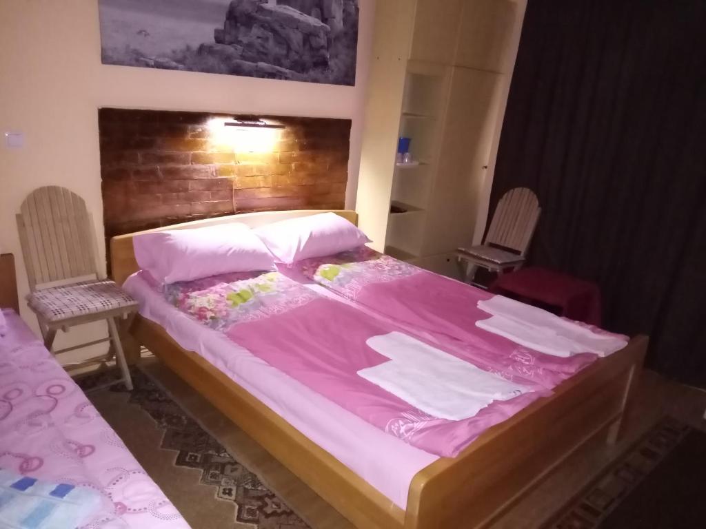 a bedroom with a large bed with pink sheets at Guest house Mirijevski Konak in Belgrade