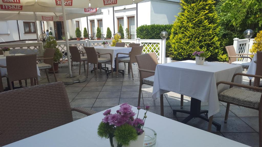 un restaurante con mesas, sillas y flores en un patio en Hotel Dworek***, en Skierniewice
