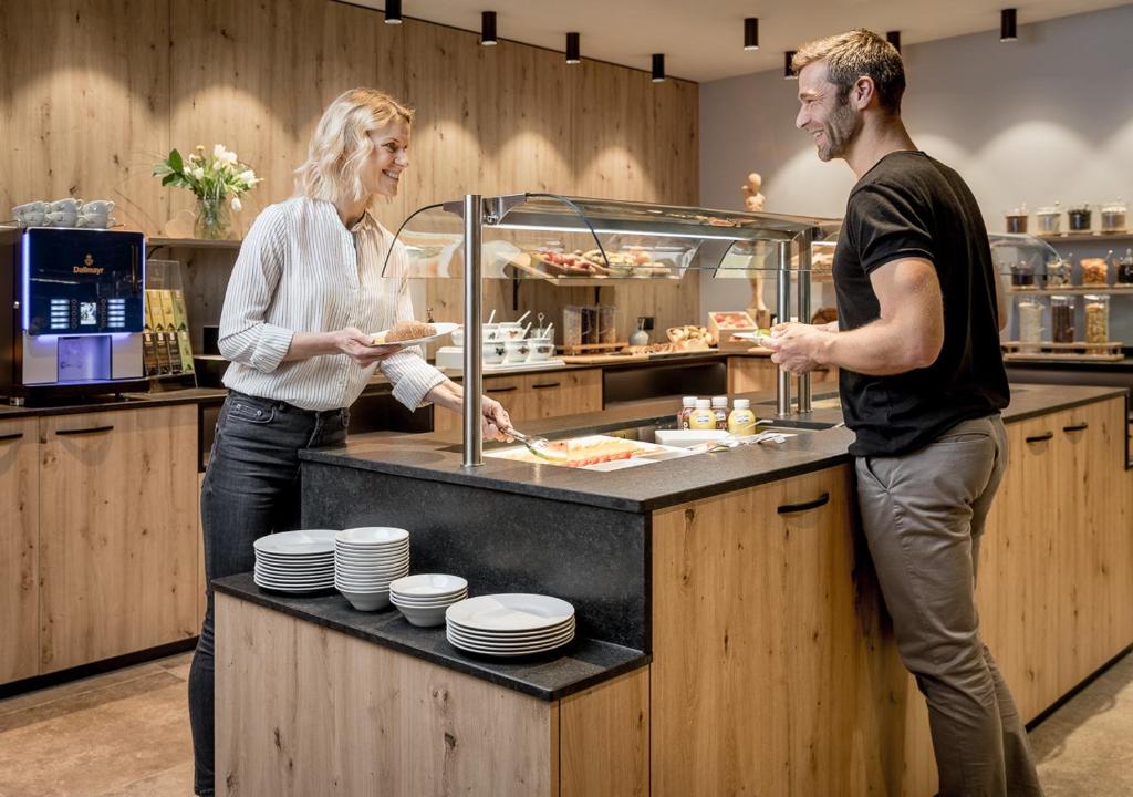 mężczyzna i kobieta stojący przy pulcie z jedzeniem w obiekcie Alpin Art & Spa Hotel Naudererhof Superior w mieście Nauders