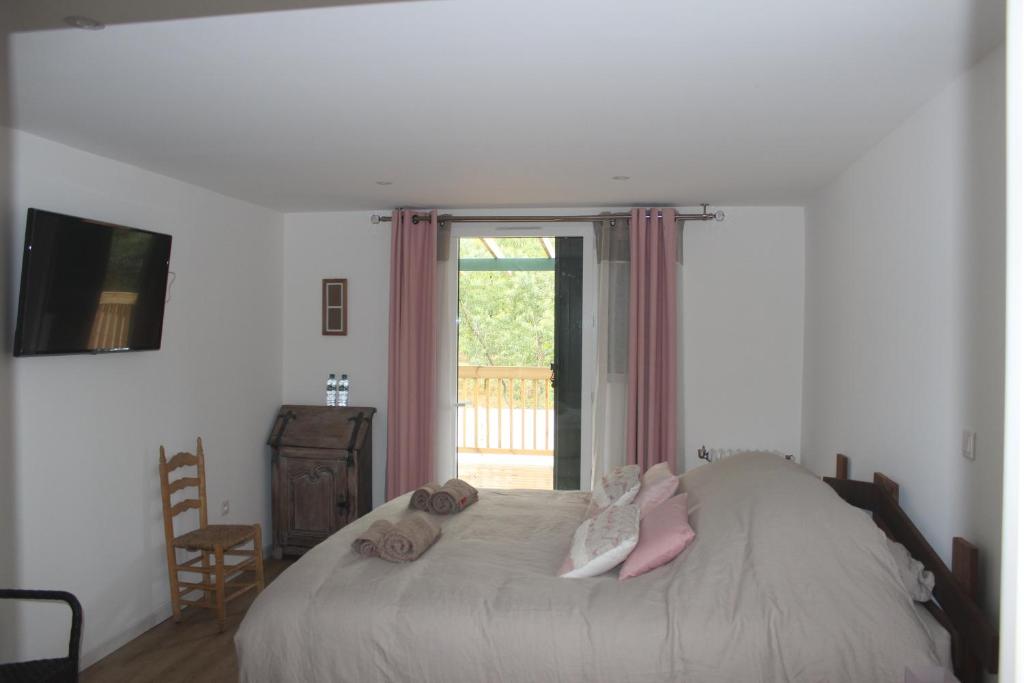 a bedroom with a bed and a window with a chair at LES CHAMBRES DU HOURON in Moliets-et-Maa