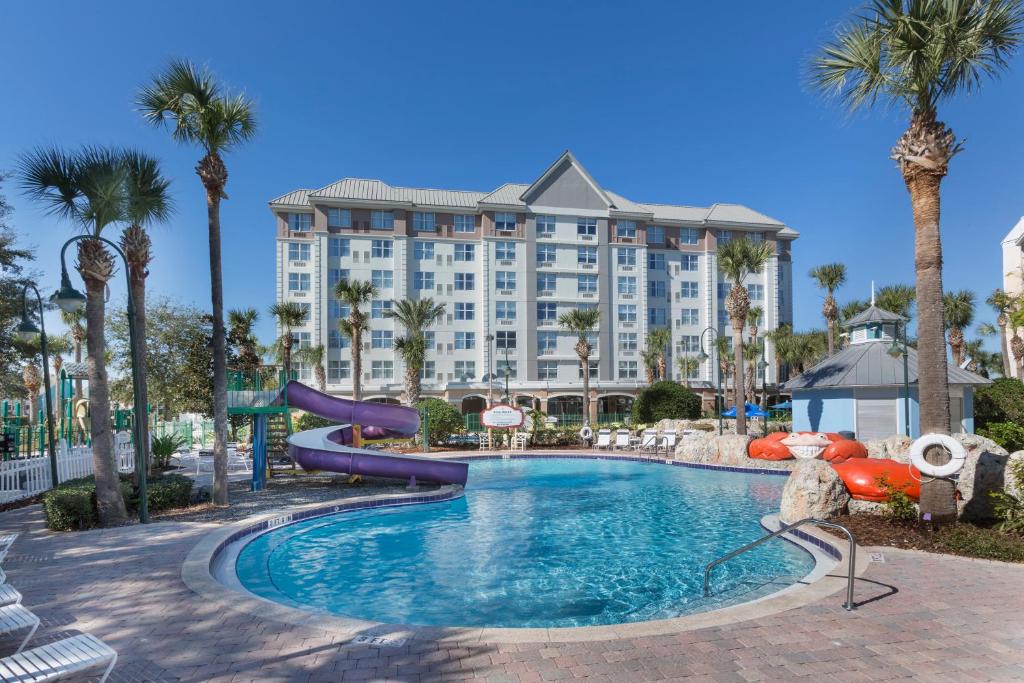 a resort with a slide in a pool with palm trees at Holiday Inn Express & Suites S Lake Buena Vista by IHG in Kissimmee