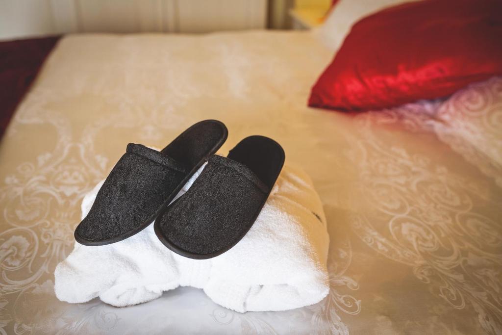two black slippers on a pile of towels on a bed at Hotel Posta in Cecina