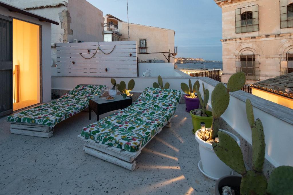 Ortigia Terrace Sea View في سيراكوزا: فناء على السطح مع كنبتين وصباب