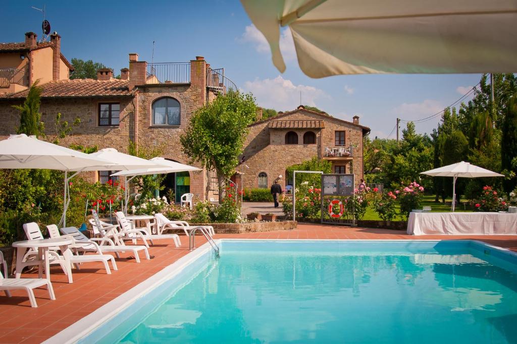 einen Pool mit Stühlen und Sonnenschirmen vor einem Haus in der Unterkunft Casa Vacanze Santa Maria in Montaione