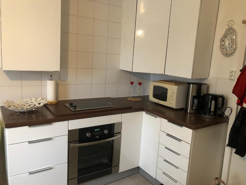 a kitchen with white cabinets and a microwave at Puutaloasunto 1 km Turun Aurajoelta föriltä in Turku