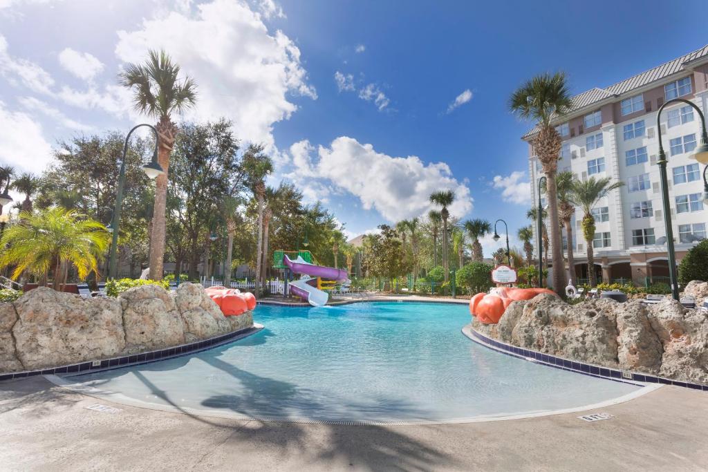 a swimming pool at a resort with palm trees at Holiday Inn Express & Suites S Lake Buena Vista by IHG in Kissimmee