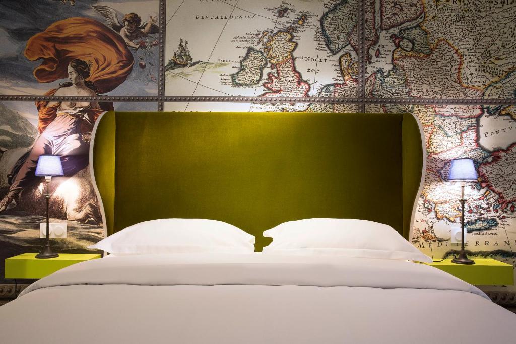 a bed with a green headboard and two lamps at Hôtel du Continent in Paris