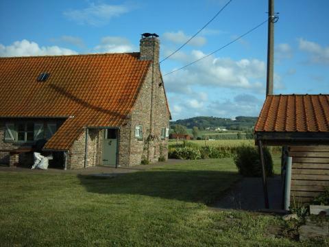 une maison en briques avec un chien debout à côté de celle-ci dans l'établissement Huis Den Keibilk, à Heuvelland