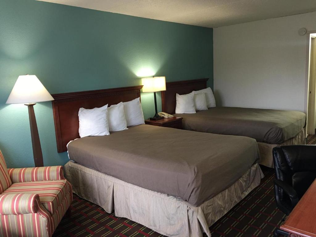 a hotel room with two beds and a chair at Fiddlers Inn Opryland in Nashville