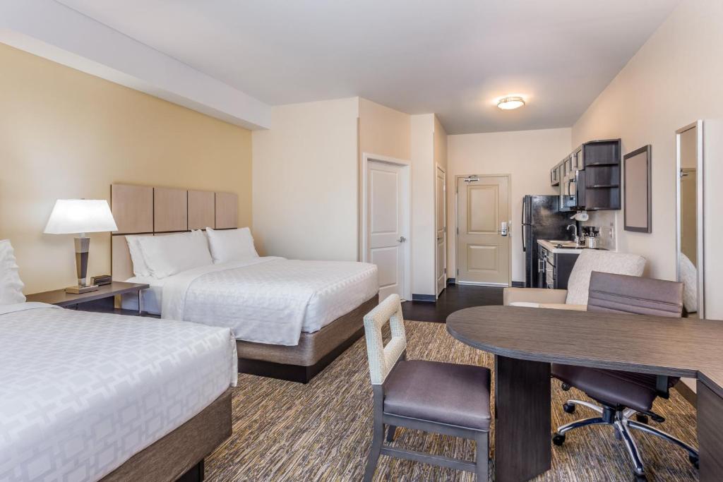 a hotel room with two beds and a desk at Candlewood Suites Bethlehem South by IHG in Bethlehem