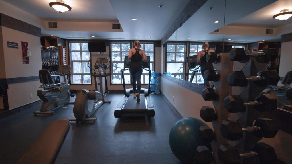 a woman walking on a treadmill in a gym at Blackcomb Springs Suites by CLIQUE in Whistler
